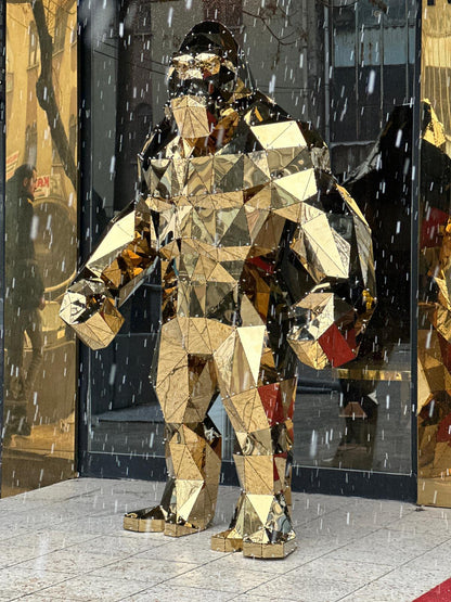Luxury gold geometric gorilla sculpture in a rainy outdoor city setting
