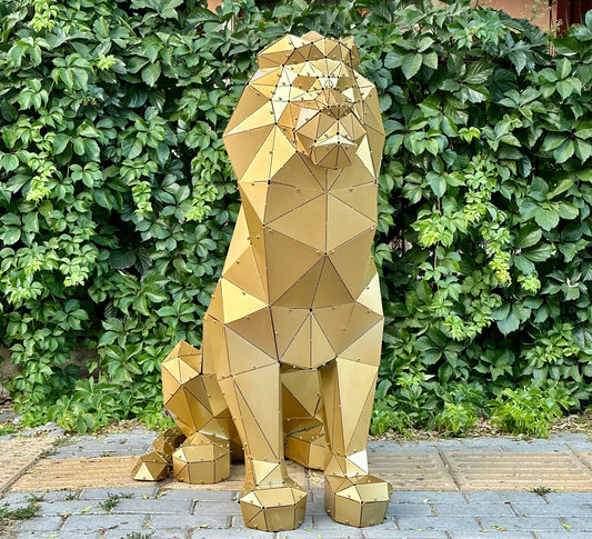 Luxury handcrafted gold geometric lion sculpture against a lush green hedge.