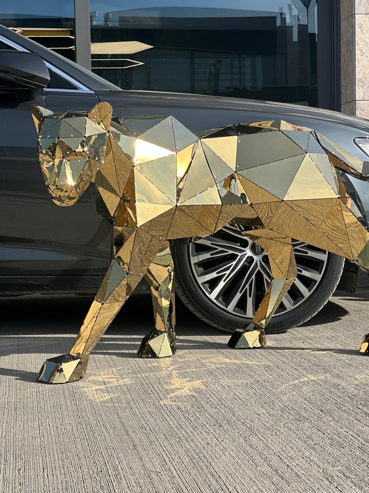 Luxury gold geometric metal panther sculpture walking beside a dark car