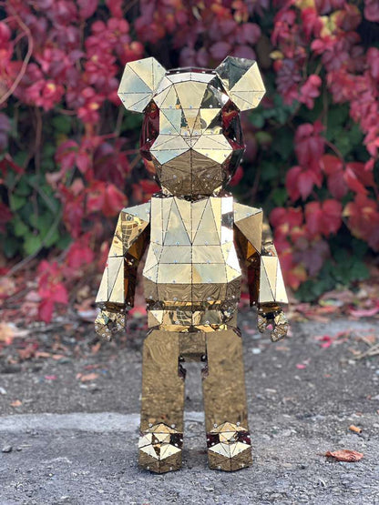 Luxury gold mirrored geometric bear sculpture standing against red autumn foliage