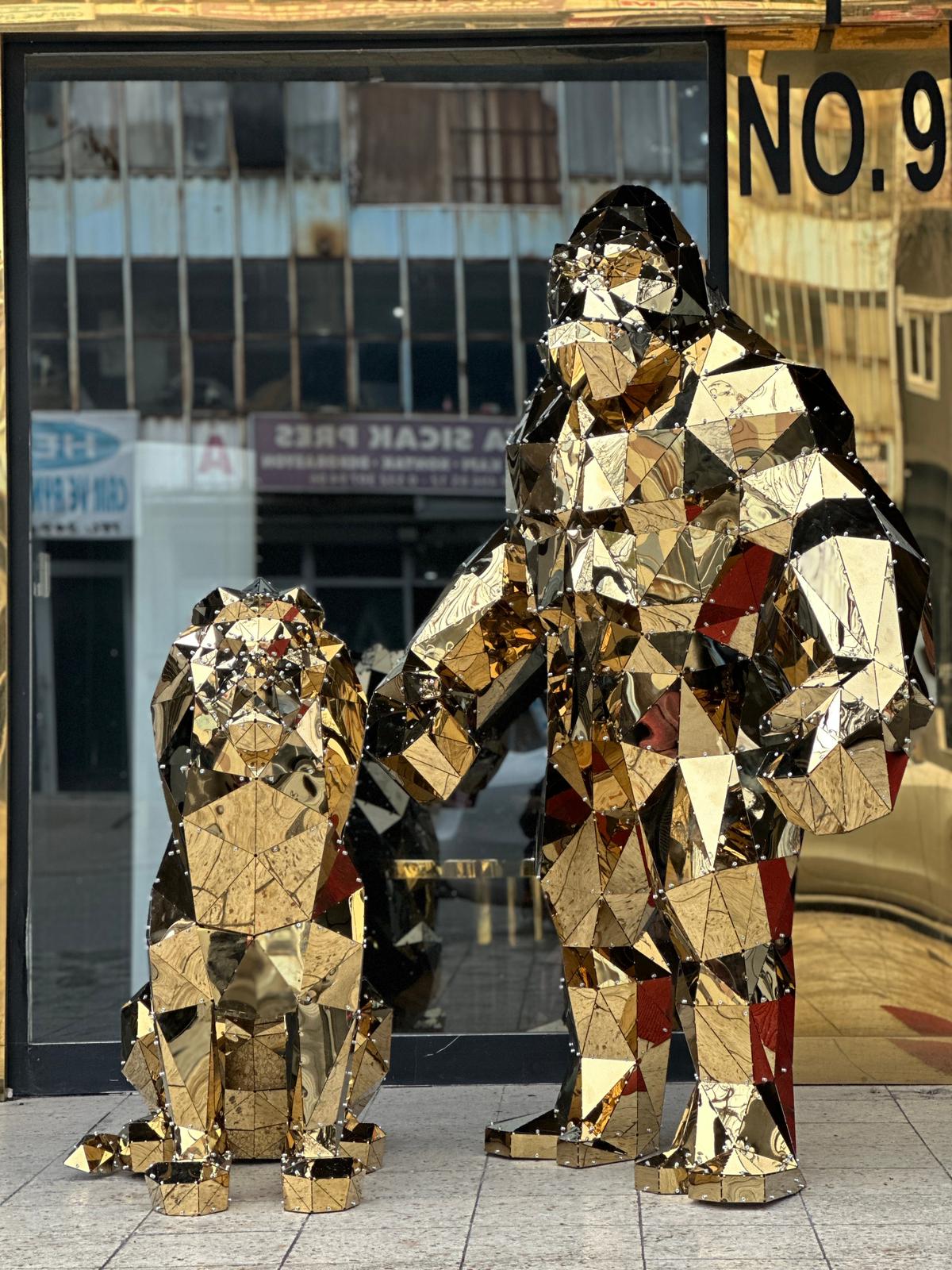 Luxury gold mirrored geometric lion and gorilla sculptures side by side in a storefront