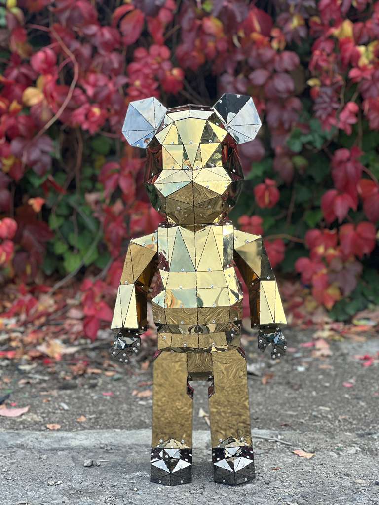 Luxury handcrafted gold geometric bear sculpture against autumn red foliage.