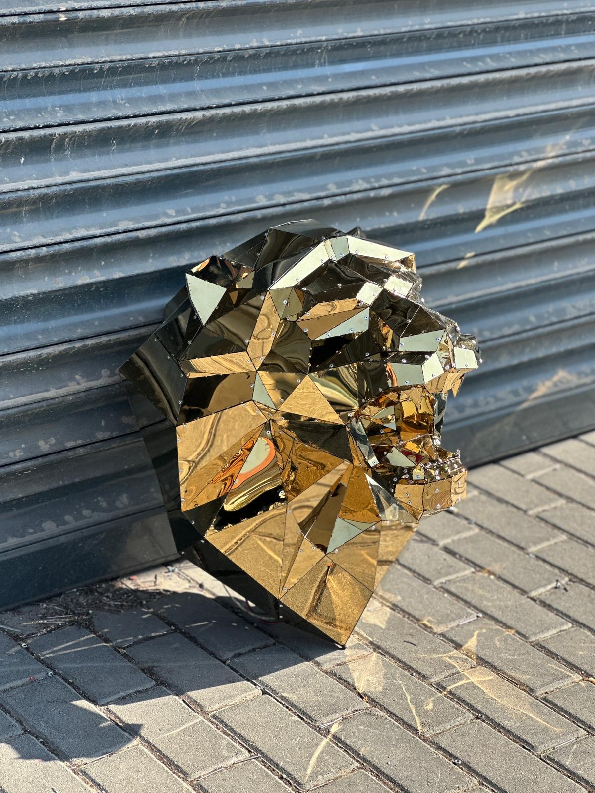 Luxury handcrafted gold geometric lion head sculpture against a grey metal shutter.