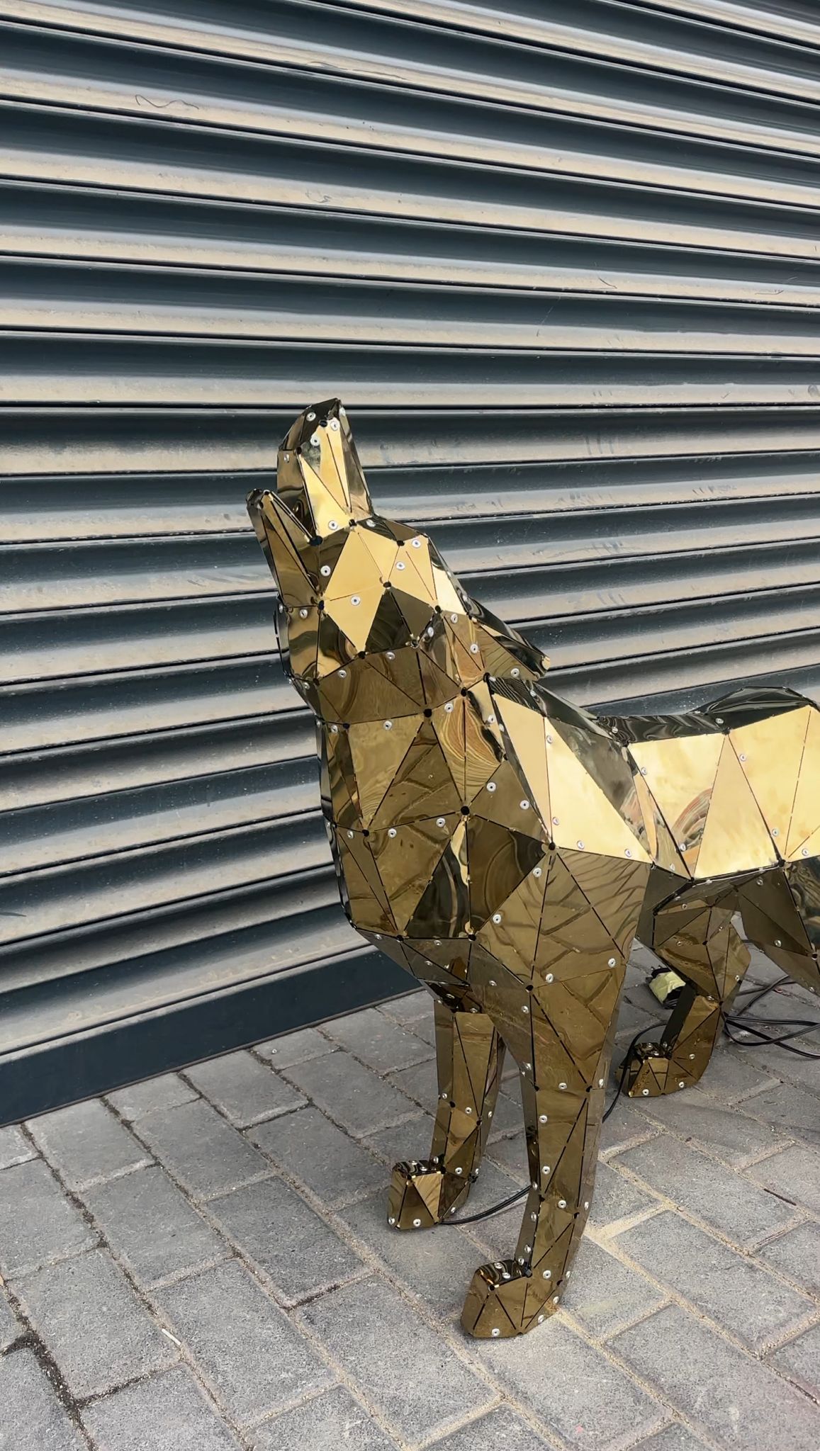 Luxury handcrafted gold geometric metal wolf sculpture against a grey shutter background.