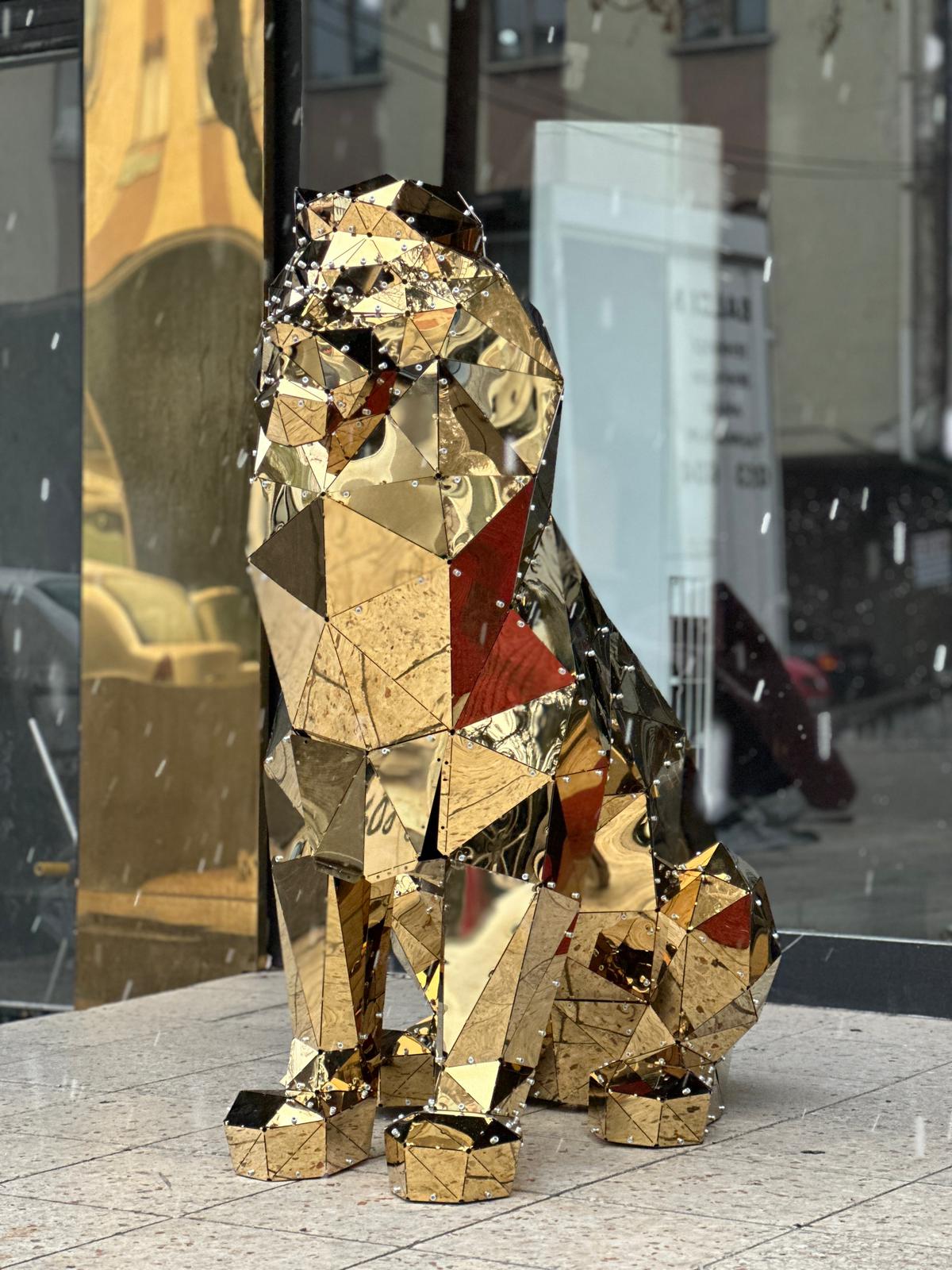 Luxury handcrafted gold mirrored geometric sitting lion sculpture in a storefront window