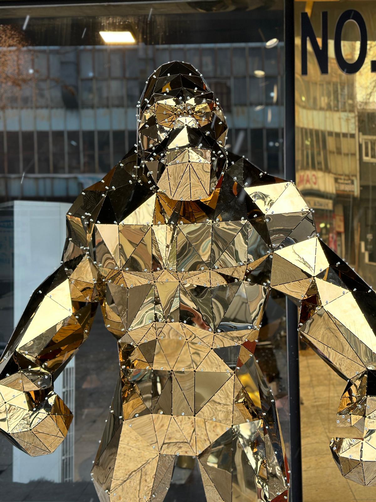 Luxury handcrafted golden geometric gorilla sculpture made of reflective mirrored metal facets.
