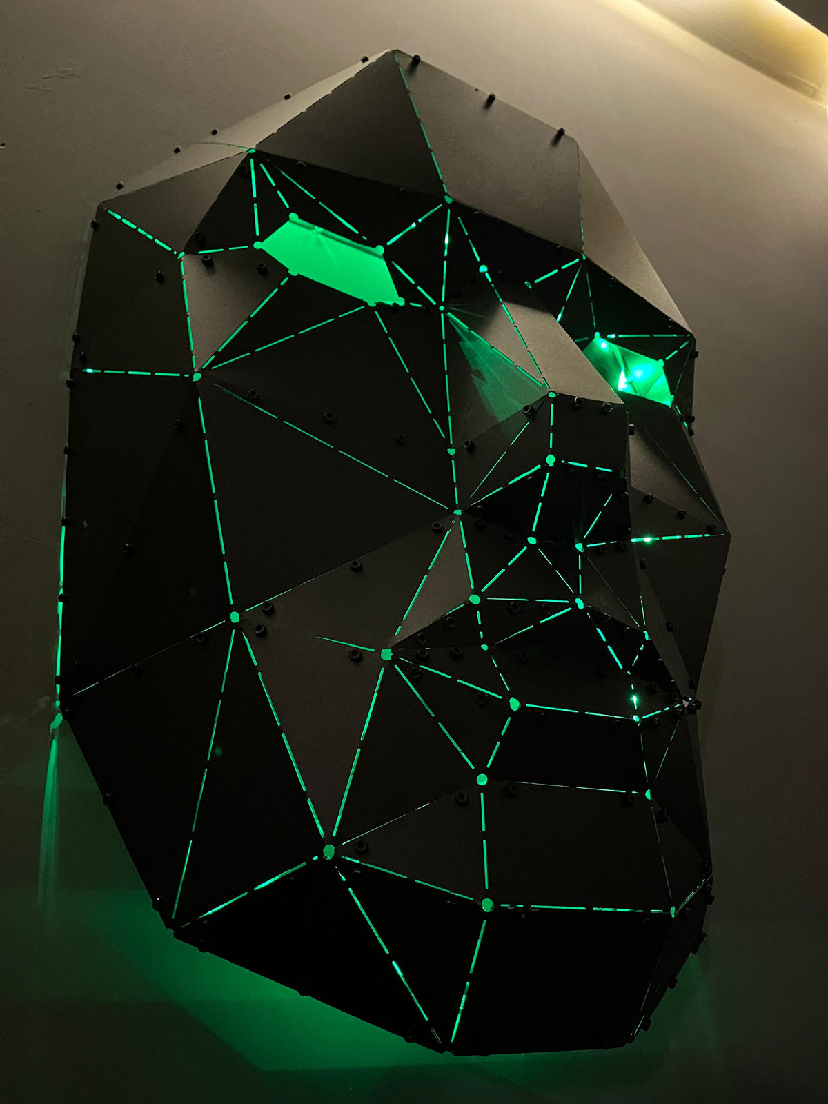 Luxury handcrafted low-poly metal face sculpture with neon green internal lighting.