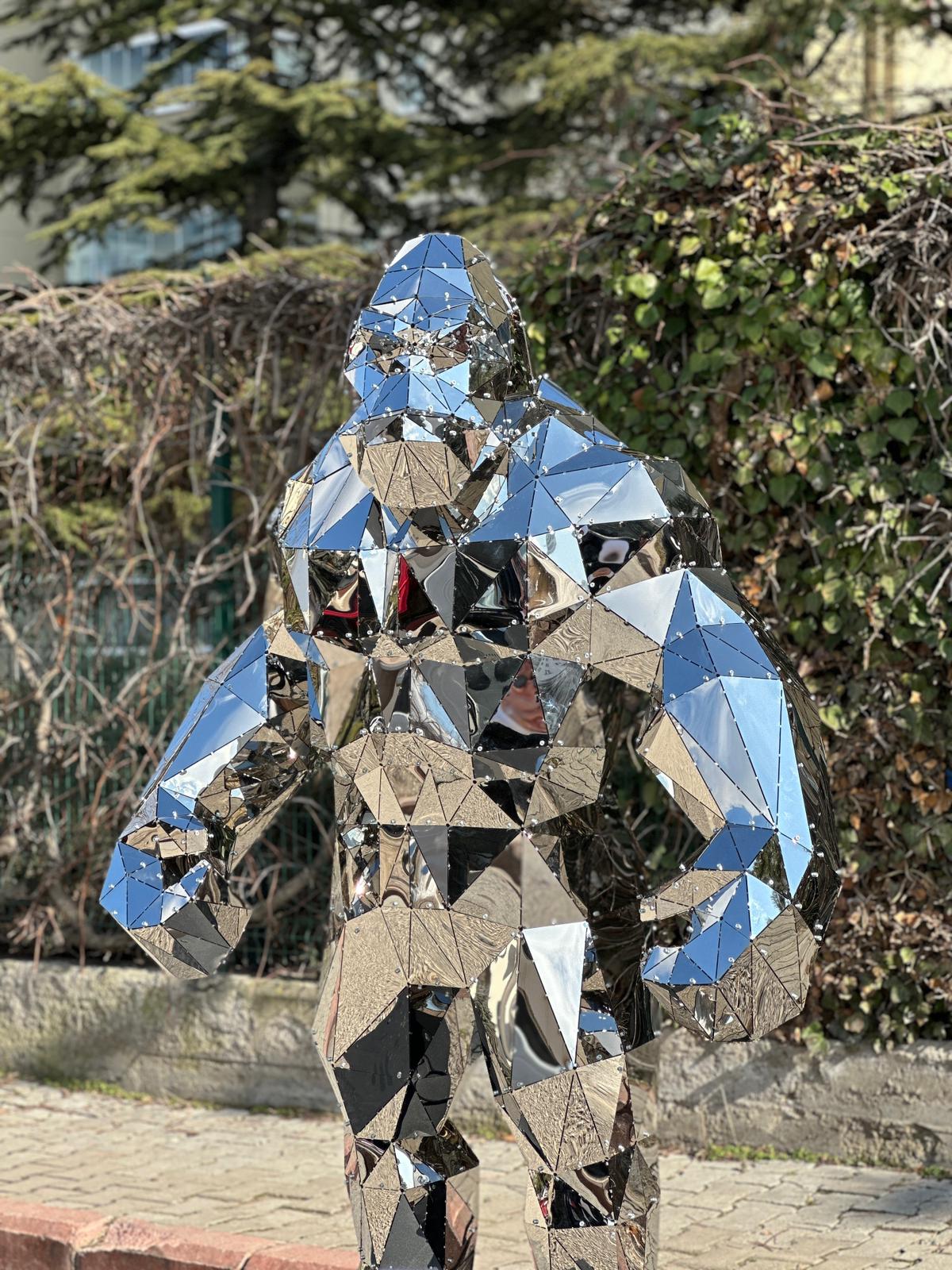 Luxury handcrafted mirrored metal gorilla sculpture with geometric faceted design outdoors