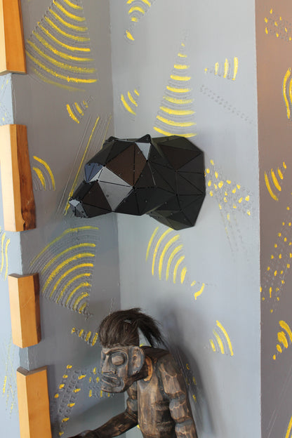 Modern black geometric bear head wall sculpture mounted on a gray wall with yellow art