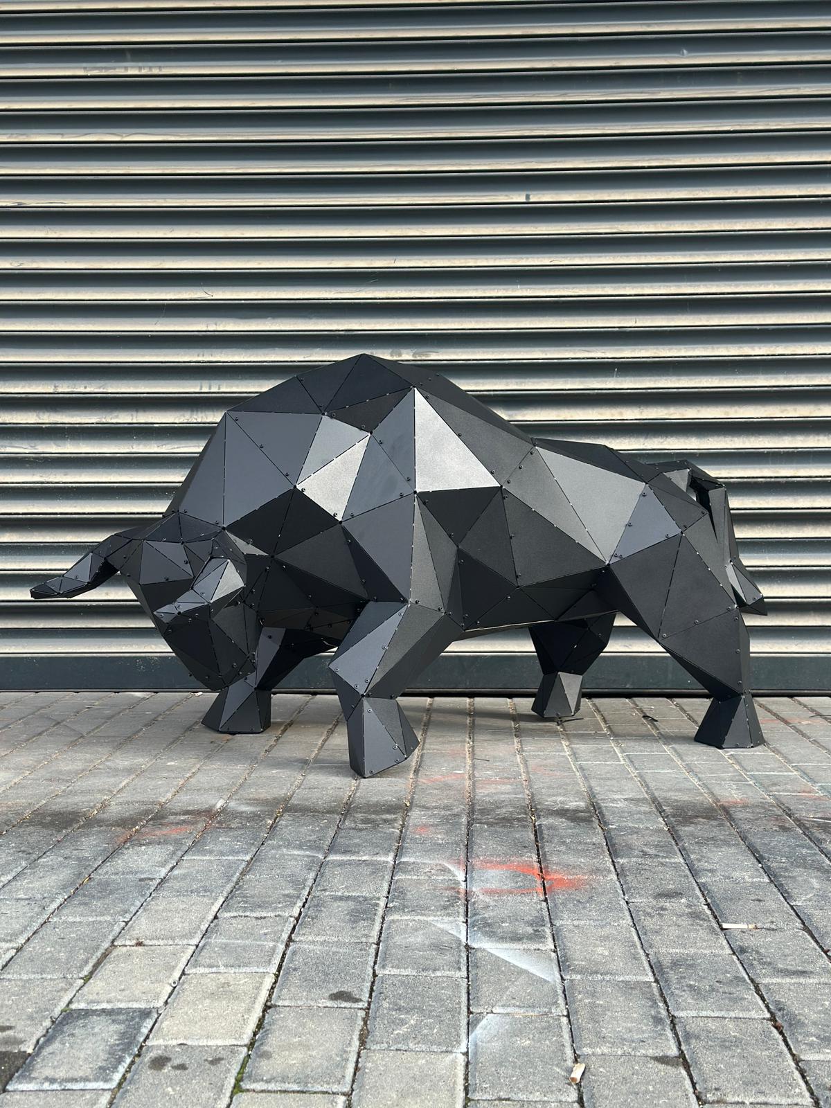Modern black geometric metal bull sculpture on a grey stone pavement