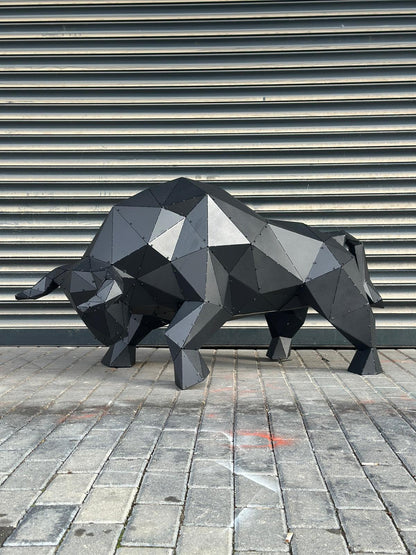 Modern black geometric metal bull sculpture on a grey stone pavement
