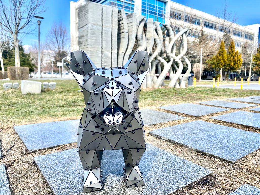 Modern geometric metal sculpture of a French Bulldog in an outdoor urban setting