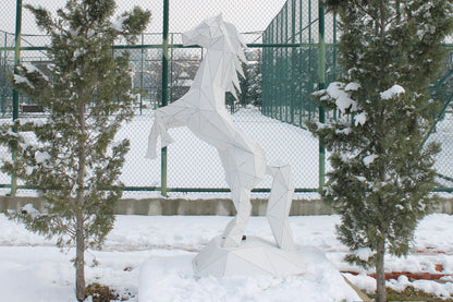 Modern geometric metal horse sculpture in a snowy outdoor setting