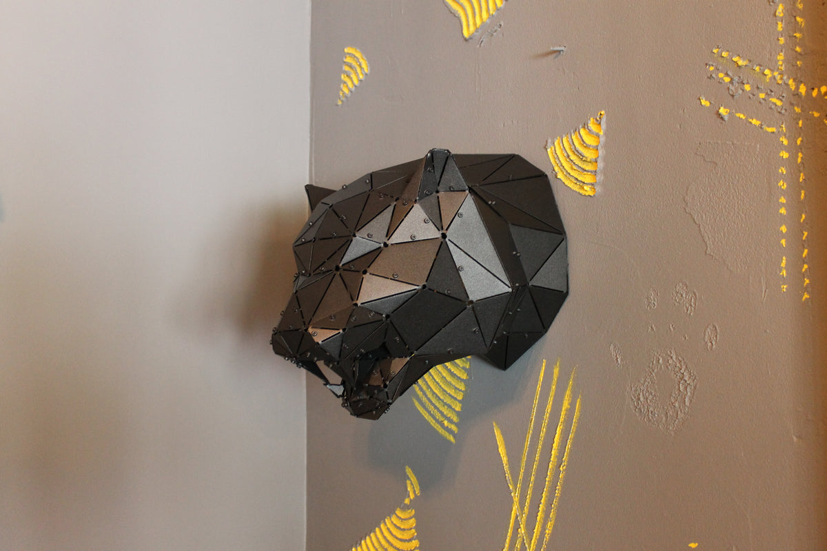 Modern low-poly geometric metal tiger head sculpture mounted on a grey wall with yellow accents