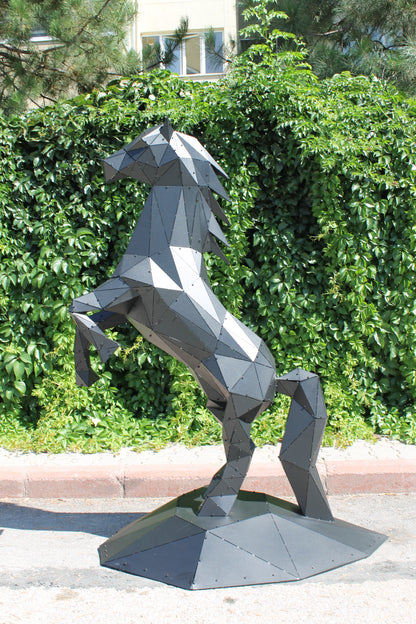Modern low-poly metal horse sculpture rearing up against a lush green hedge background.