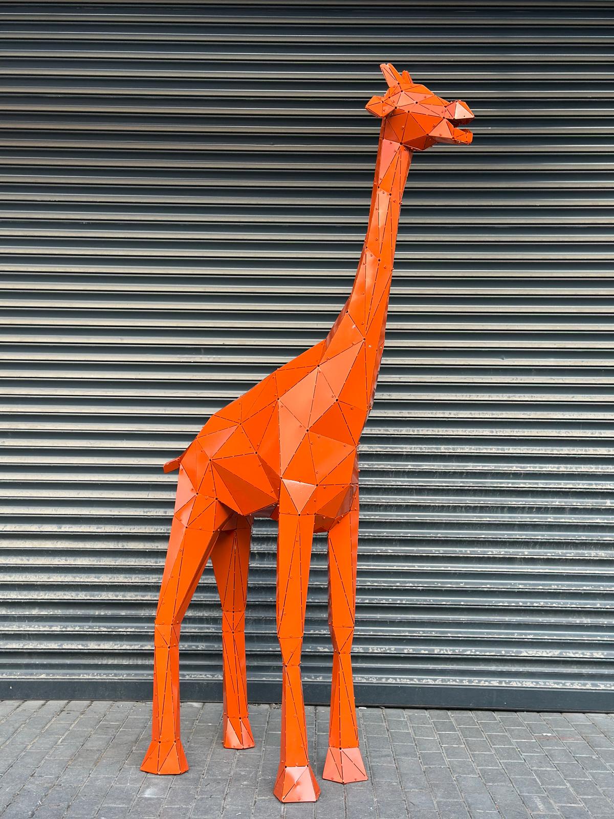 Orange geometric metal giraffe sculpture against a grey corrugated shutter background.