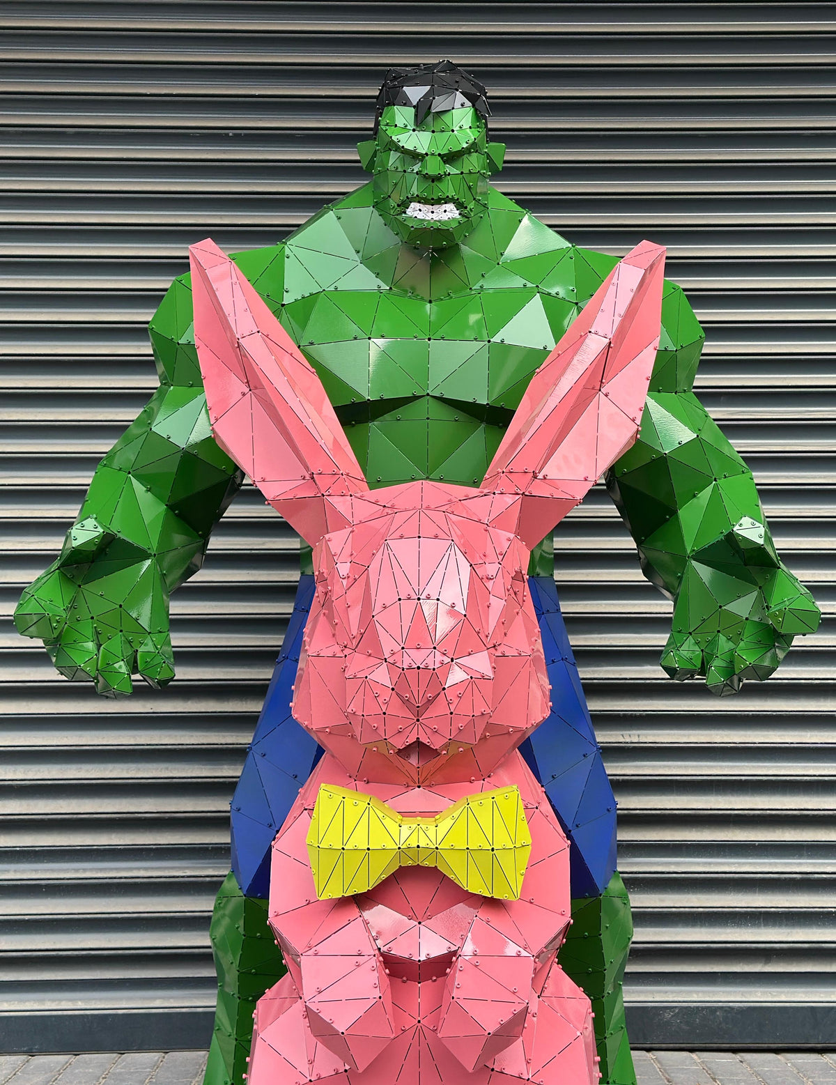 Low-poly metal sculpture of the Hulk and a pink rabbit with a yellow bowtie.