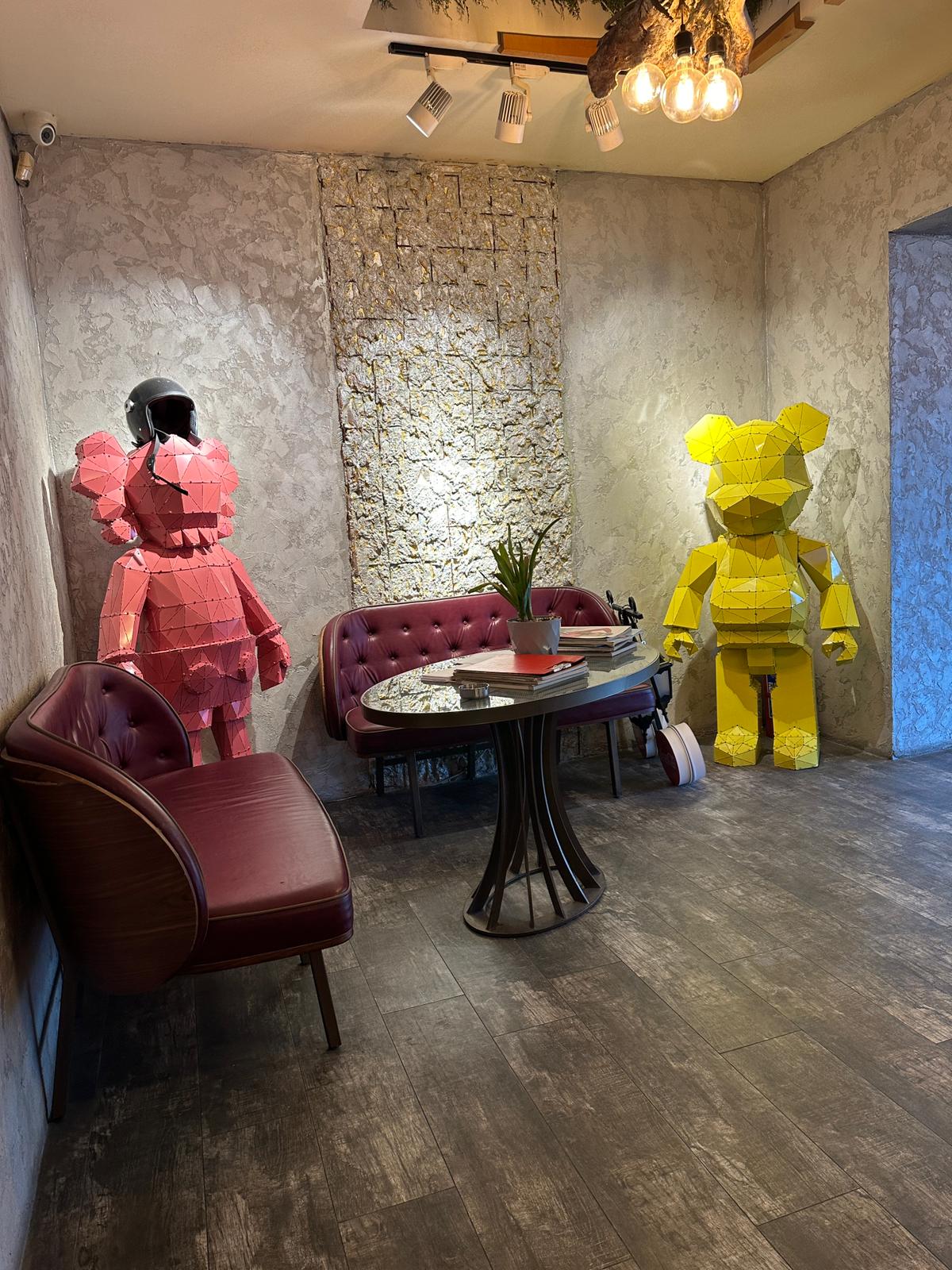 Modern interior with red and yellow handcrafted metal bear sculptures and luxury furniture.