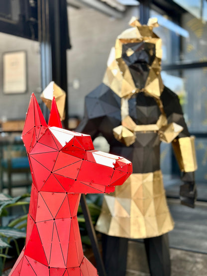Red geometric metal fox sculpture in foreground with a gold and black figure behind.