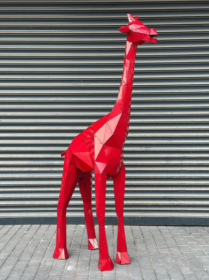 Red geometric metal giraffe sculpture standing against a grey corrugated wall