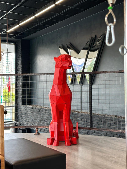 Red geometric metal sculpture of a sitting animal in a modern industrial interior