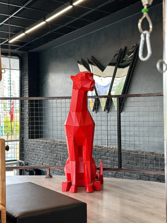 Red geometric metal sculpture of a sitting animal in a modern industrial interior
