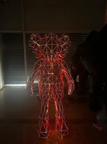 Red illuminated geometric wireframe sculpture of a stylized character in a dark room