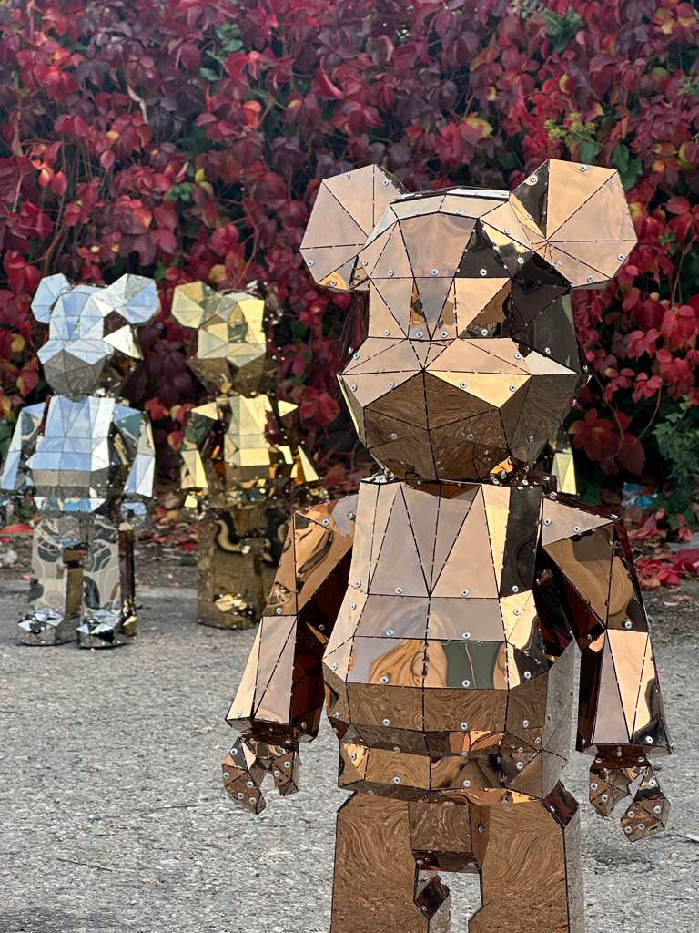 Three faceted geometric bear sculptures in copper, gold, and silver metal finishes.