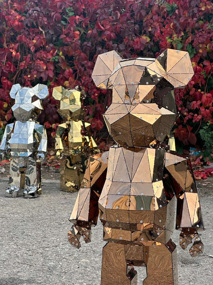 Three faceted geometric bear sculptures in copper, gold, and silver metal finishes.