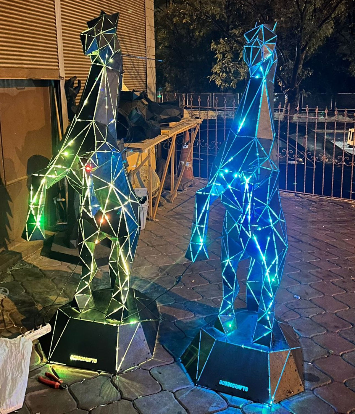 Two geometric metal rearing horse sculptures illuminated with green and blue LED lights