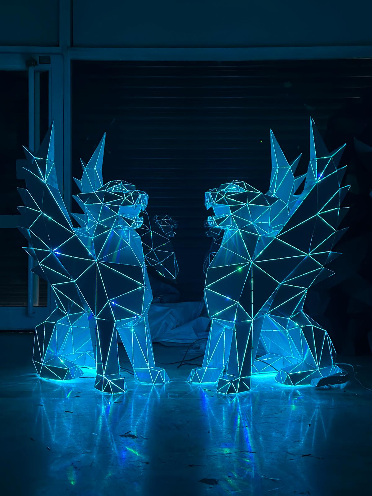Two low-poly geometric griffin sculptures illuminated with blue LED lights