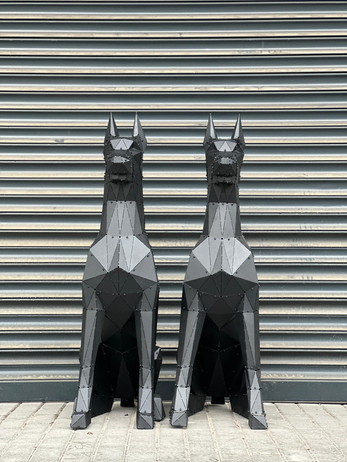 Two luxury handcrafted black metal Doberman dog sculptures in a geometric low-poly style.