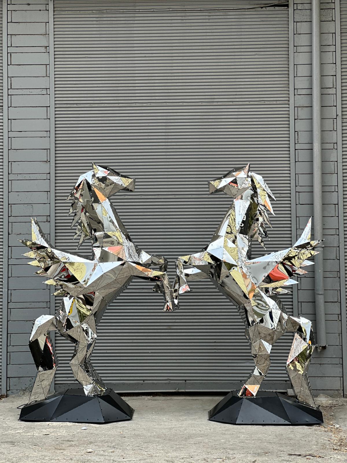 Two mirrored polygonal metal pegasus sculptures facing each other against a grey shutter.