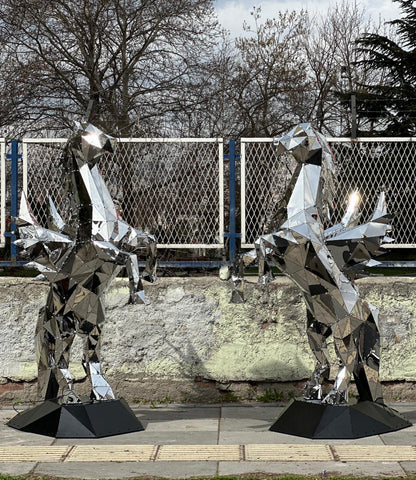 Two mirrored stainless steel geometric horse sculptures facing each other outdoors.