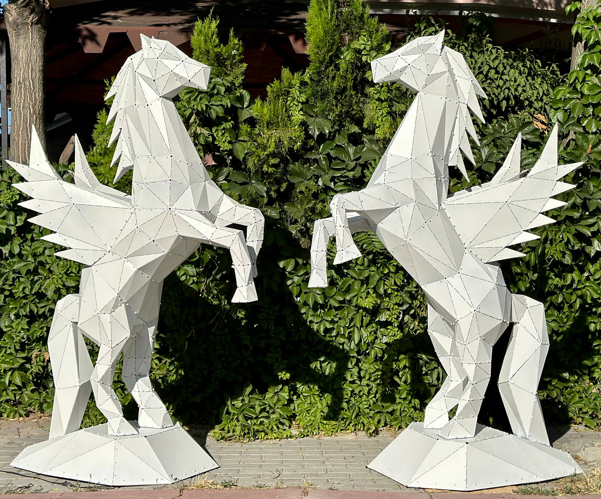 Two white geometric metal Pegasus sculptures facing each other against a green hedge.