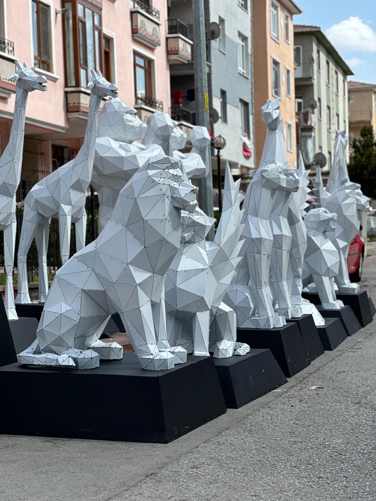 Line of geometric white metal animal sculptures including lions and giraffes on a city street