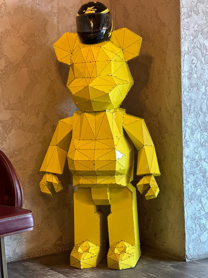 Handcrafted yellow geometric metal bear sculpture wearing a black motorcycle helmet
